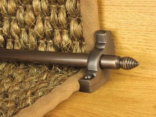 Antique brass stair rod with beehive finial on a natural fiber runner.
