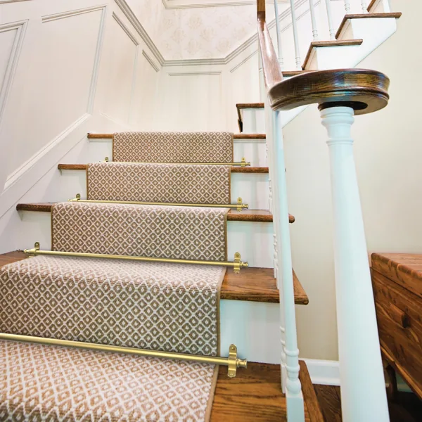 Brass stair rods securing a patterned runner on a staircase.