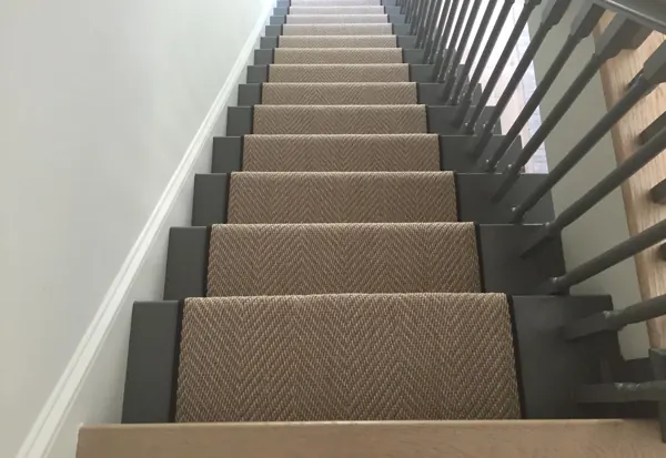 Brown herringbone stair runner on grey stairs.