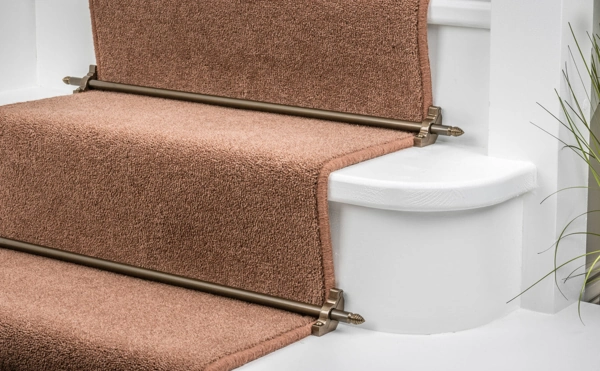 Brown textured stair runner secured on white stairs with antique bronze stair rods