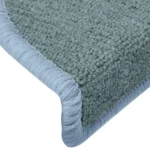 Close-up view of a blue-grey carpet stair tread showing textured loop pile weave and light blue bound trim.