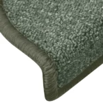 Close-up view of textured dark green carpet stair tread with wrapped bullnose edge.