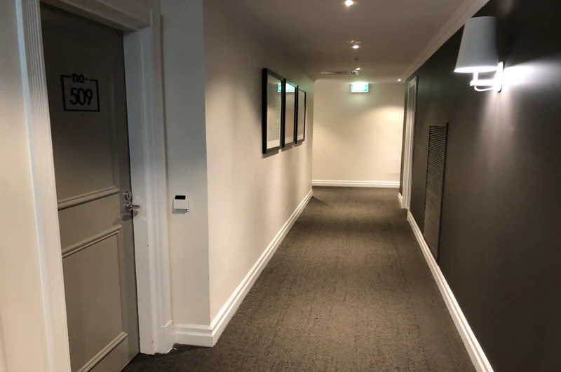 Dark grey carpeted hotel hallway with white trim