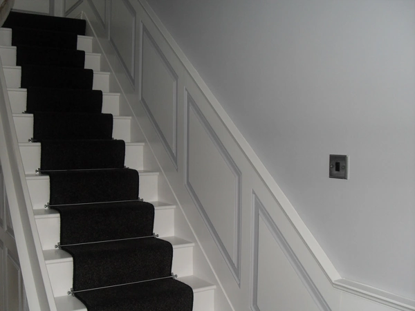 Dark wool stair runner with silver stair rods on white stairs