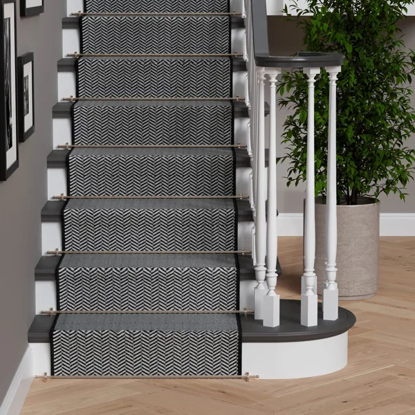 Gold-toned stair rods securing a black-and-white herringbone runner on a staircase.