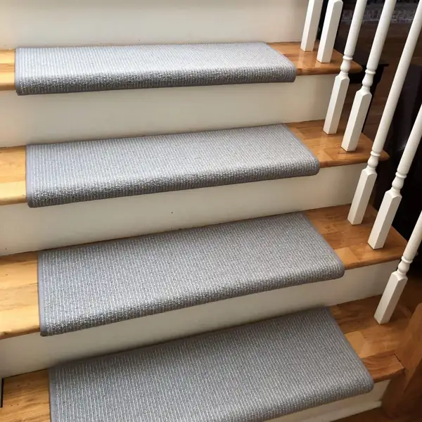 Gray ribbed carpet stair treads with bound edges on wooden steps