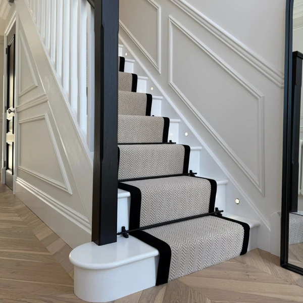 Grey chevron wool stair runner with black binding and stair rods.