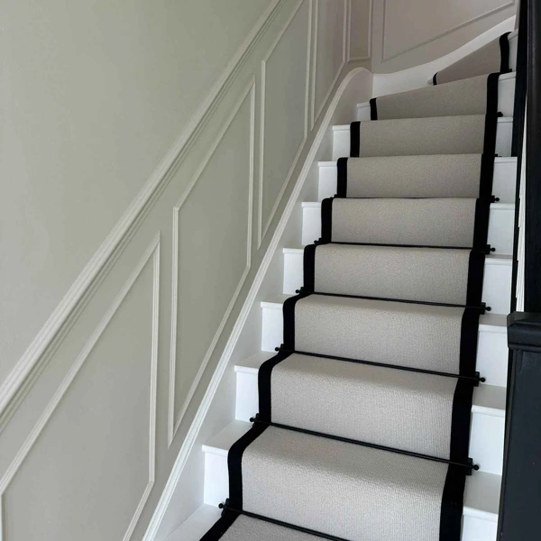 Grey wool stair runner with black border and black stair rods.