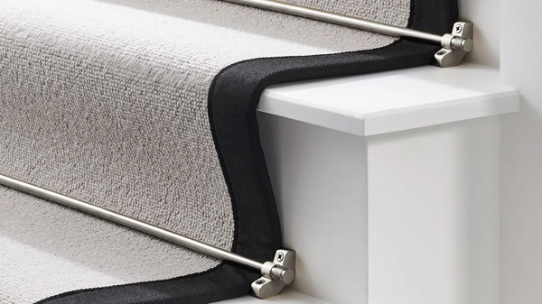 Light gray carpet with a black border secured on white stairs