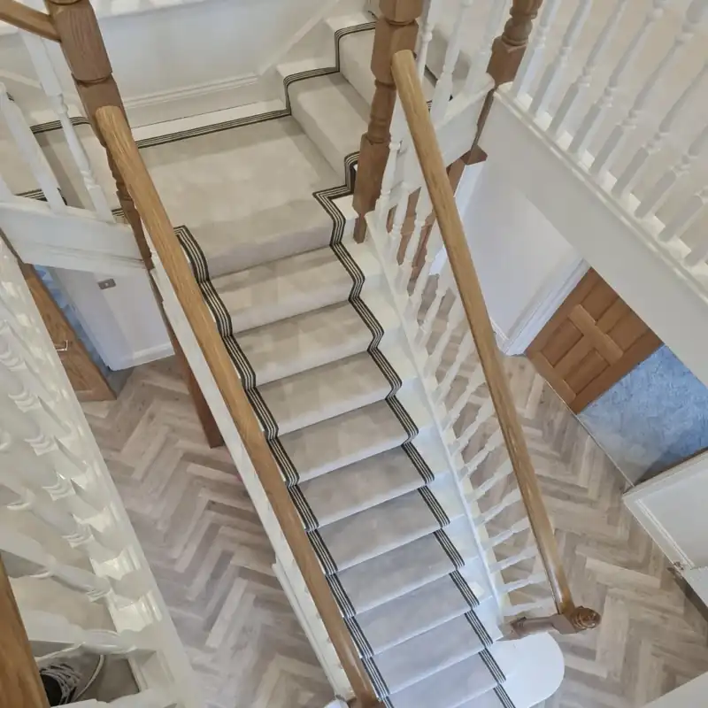 Light grey stair runner with a thin black striped border on white stairs