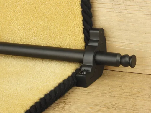 Matte black stair rod on a yellow carpet runner with a black border.