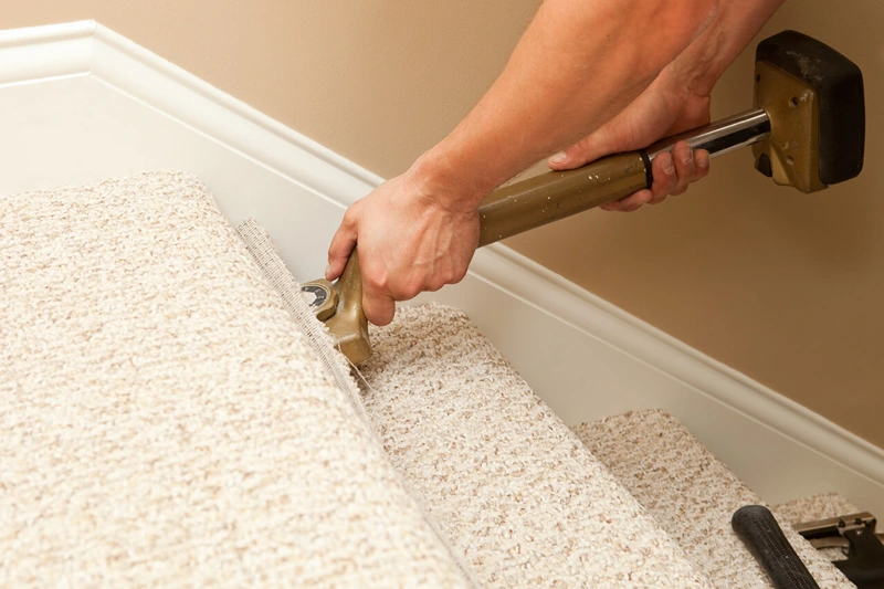 Stretching carpet onto stairs with knee kicker tool