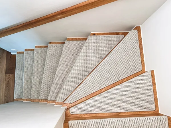 Textured beige carpet stair treads on wooden winding stairs