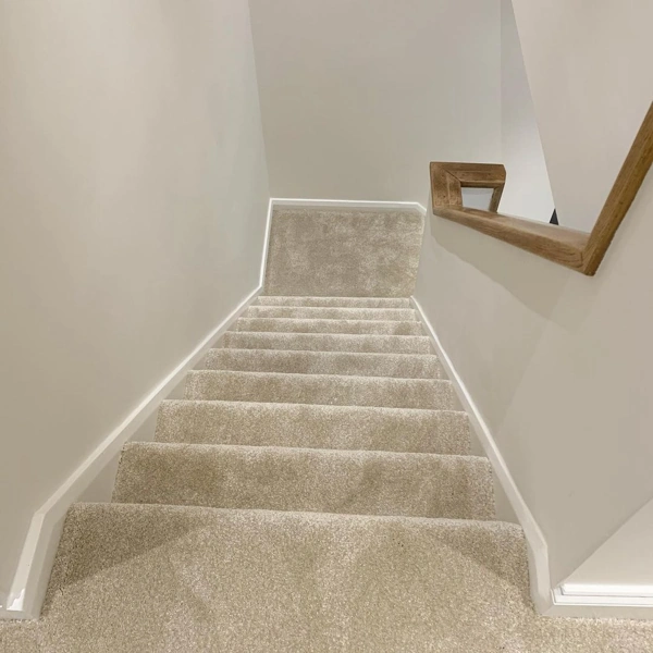 Top-down view of fully carpeted beige home staircase