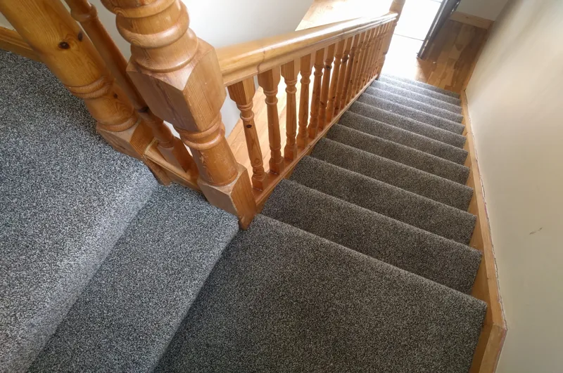 Wooden staircase fully fitted with grey carpet
