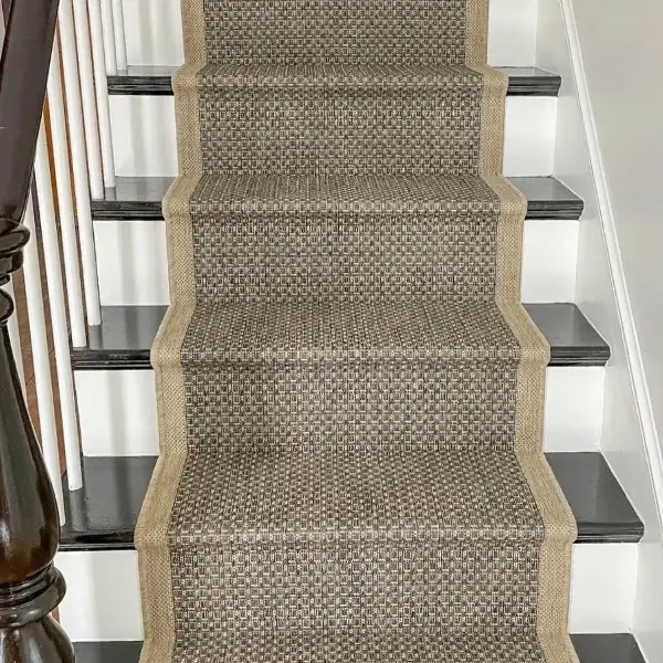 Woven patterned sisal stair runner on black step treads