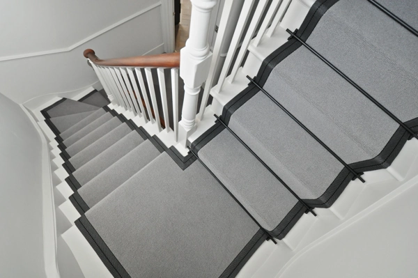 dark patterned borders and black stair rods on a white staircase.