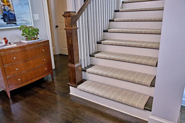 patterned carpet stair treads on white stairs with dark wooden edges.